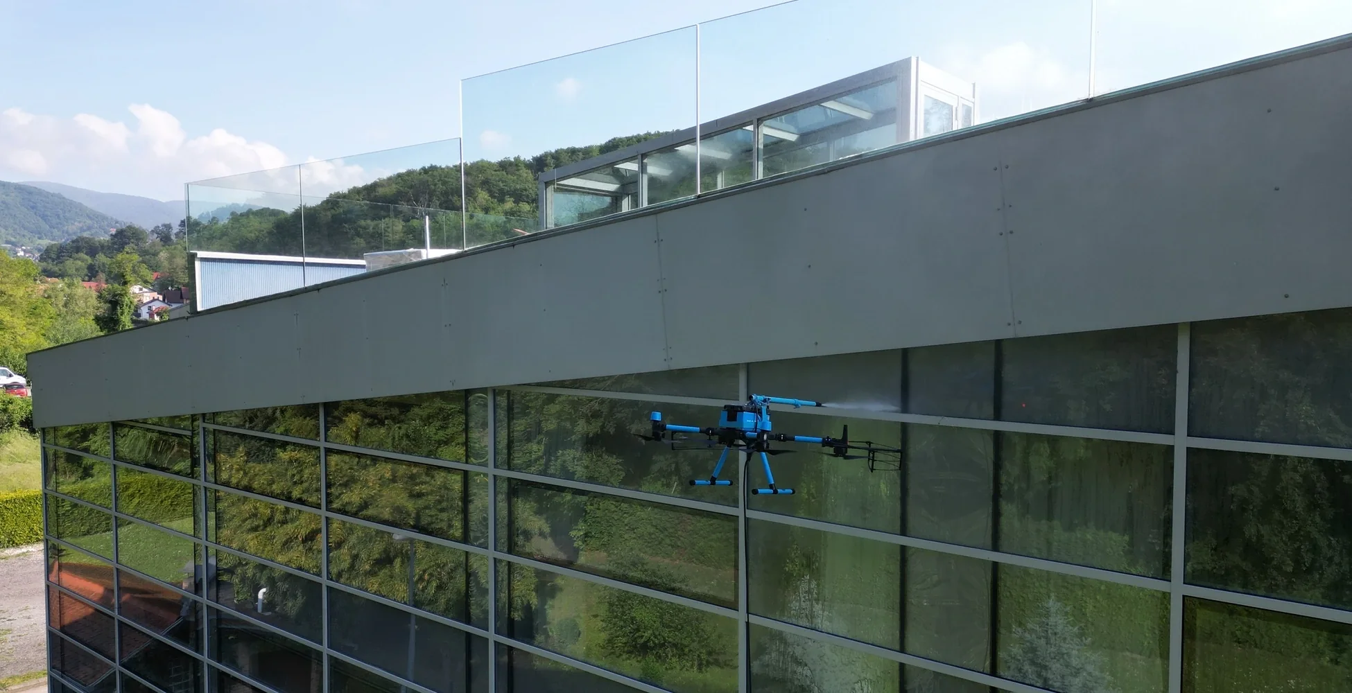 Drone washing the glass facade of an office building at height